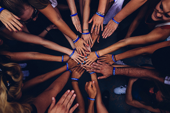 Multiracial hands reaching together in a circle.