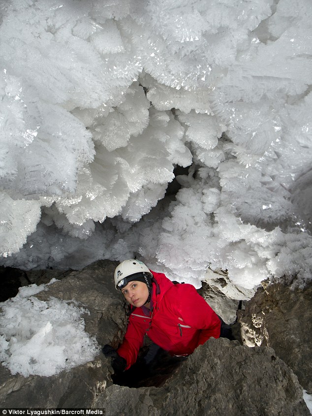 A caver stands next to stunning  build up of ice on the roof of the Kungur cave