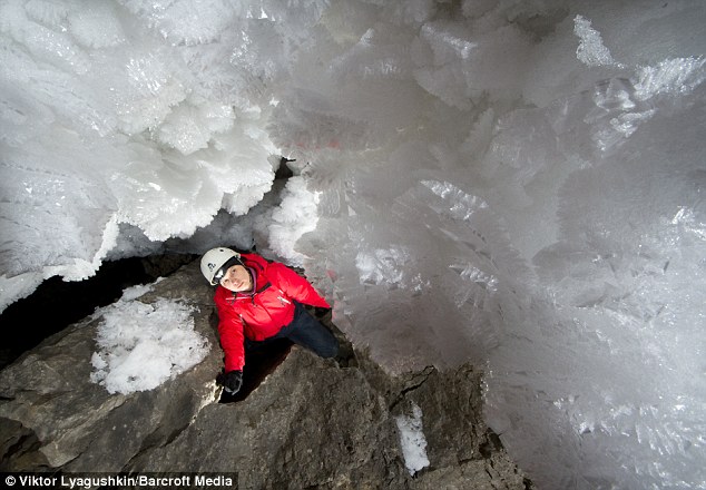A caver stands next to ice crystals in the Kungur ice caves