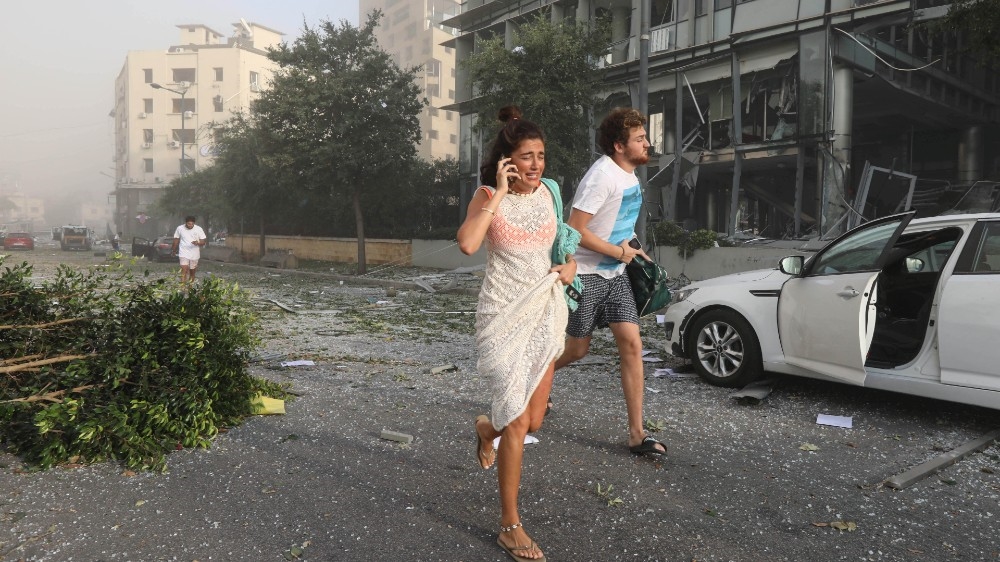 People run for cover following an explosion in Beirut